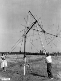 Mann und Frau beim Aufrichten der Antenne des Feldstärkenmessers FSM auf freiem Feld, August 1958.