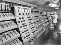 Frau im weißen Arbeitskittel bei der Lebensdauerprüfung von Empfängerröhren, September 1965.