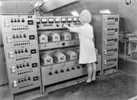 Frau im weißen Arbeitskittel bei der Lebensdauerprüfung von Wanderfeldröhren, September 1965.